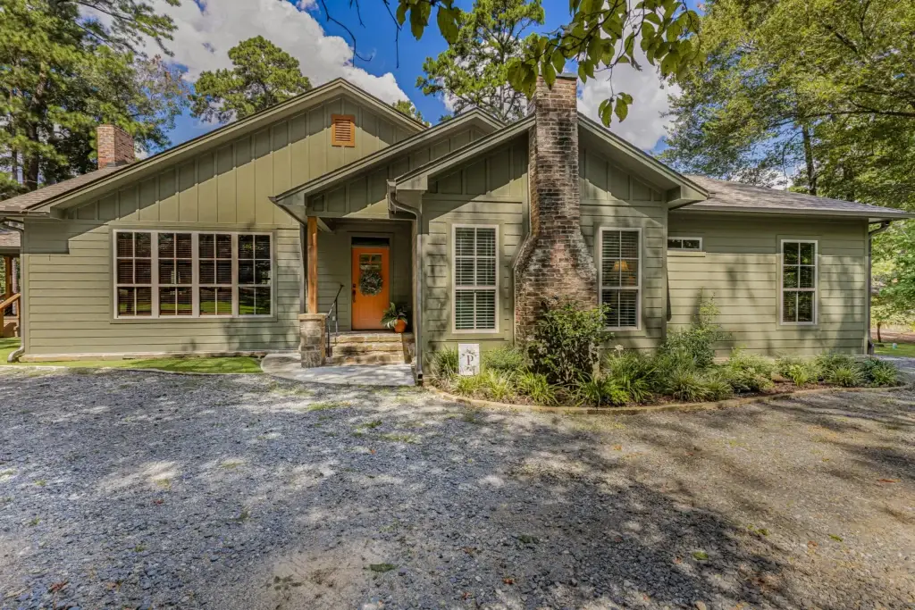 Front of the Fern Lake house with green siding, an orange front door and a brick chimney