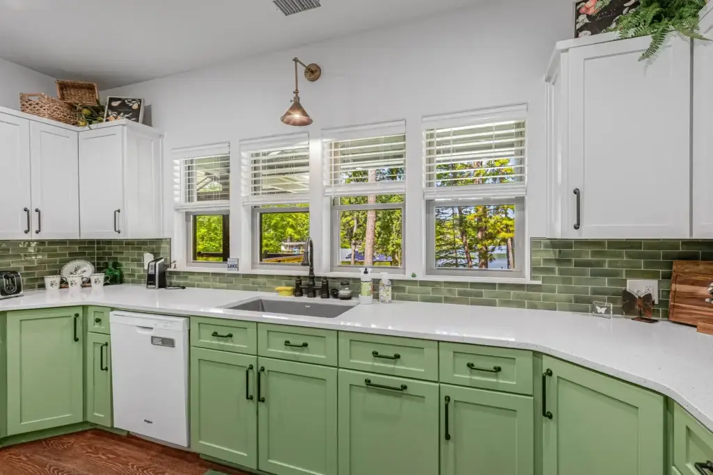 Kitchen sink under a row of windows with a green tile backsplash