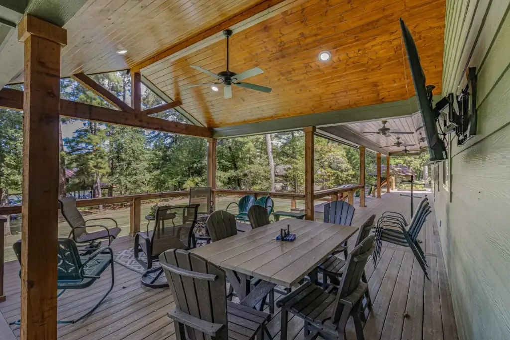 Back porch dining area under a wood plank ceiling with ceiling fans